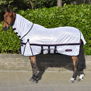 Horse wearing a white fly sheet with black straps in front of green bushes.